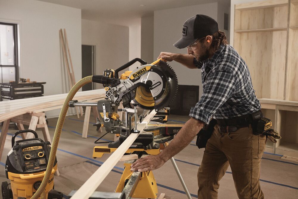 A tradesperson uses a DEWALT miter saw to cut trim pieces