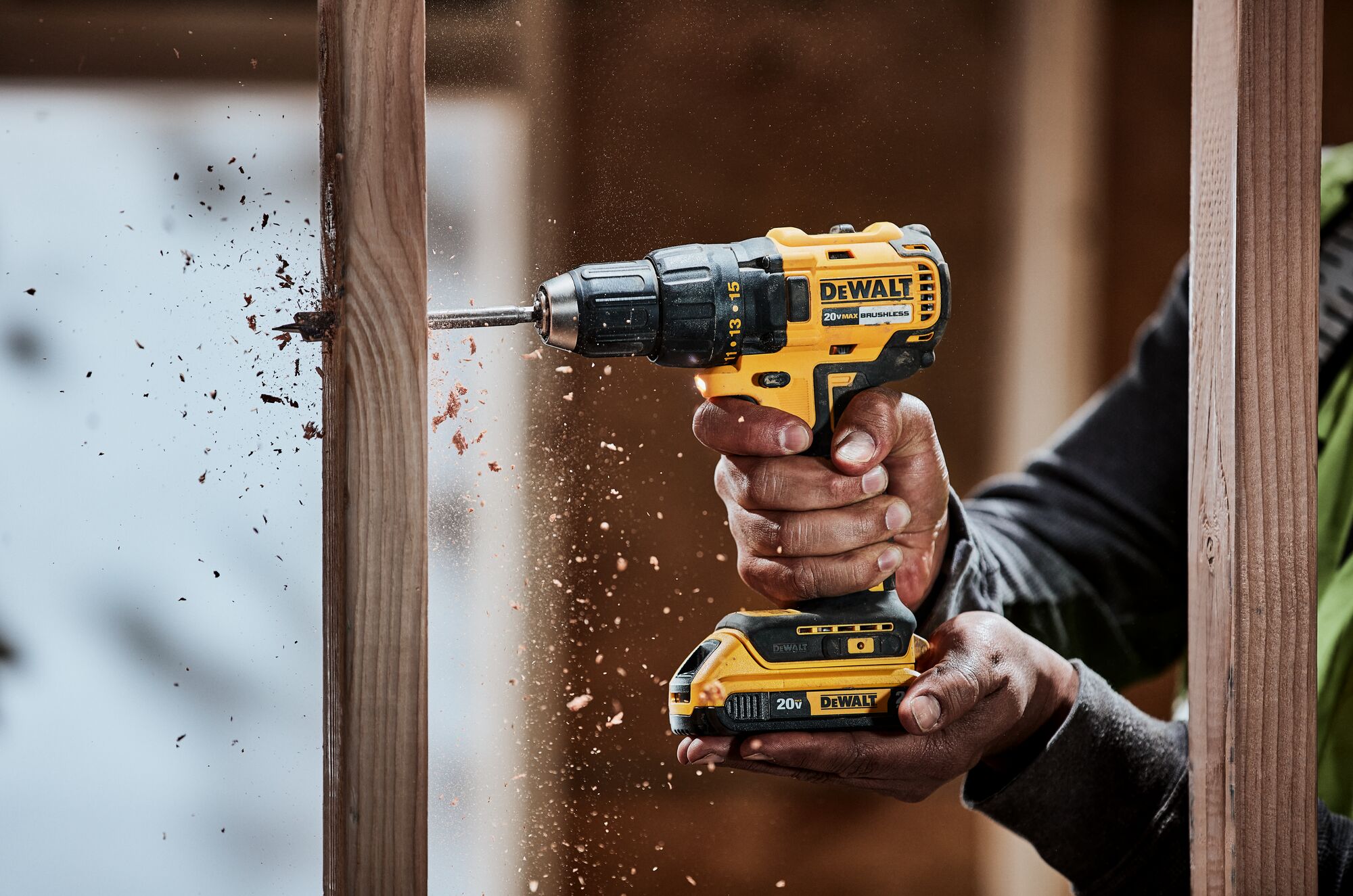 DEWALT Regular Drill powered by a 20V 2Ah battery, used by a bare hands worker drilling a wooden structure.