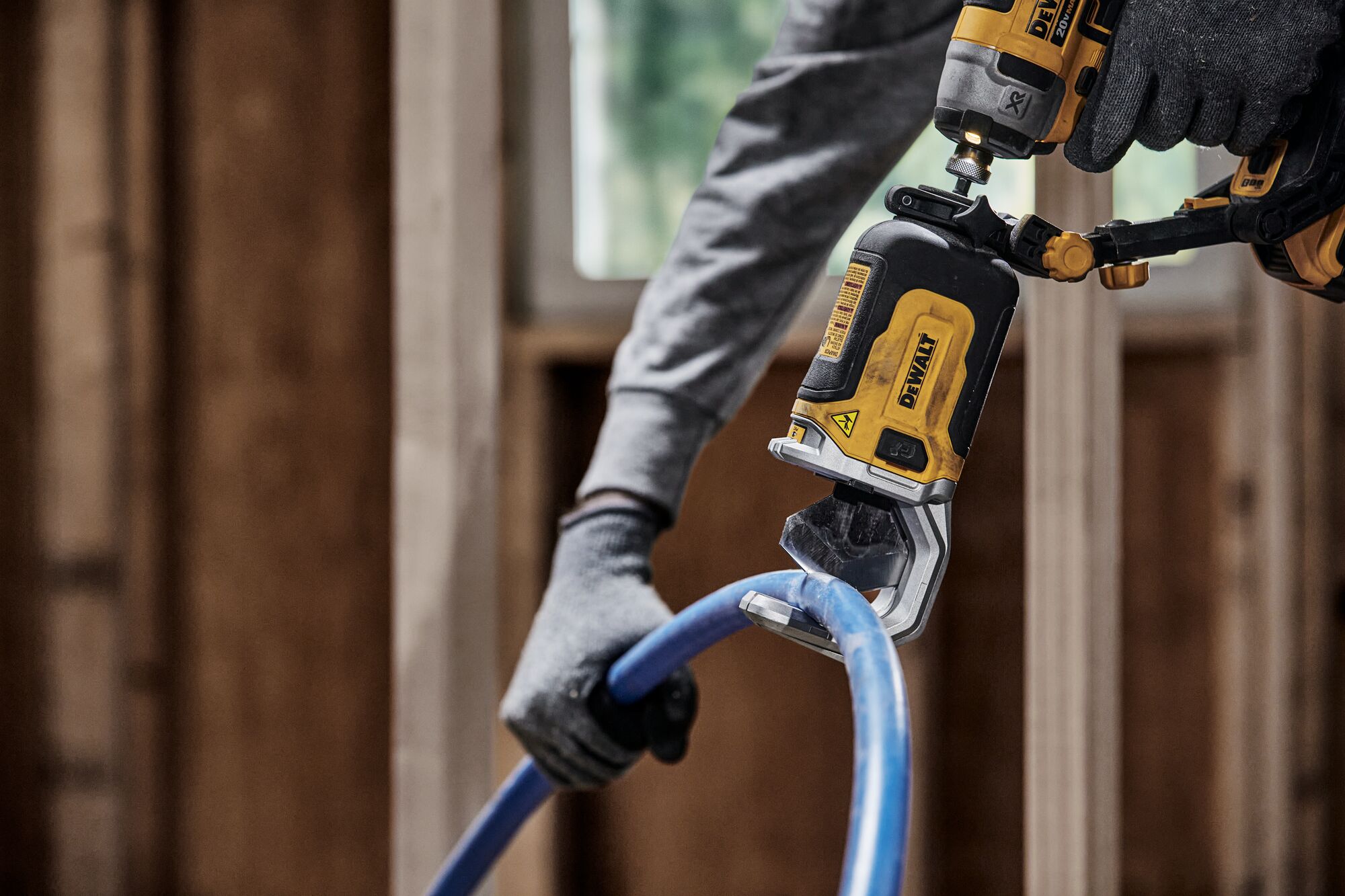 End user using DEWALT IMPACT CONNECT PVC/Pex Cutter attachment on Impact Driver to cut pex tubing near wood framing