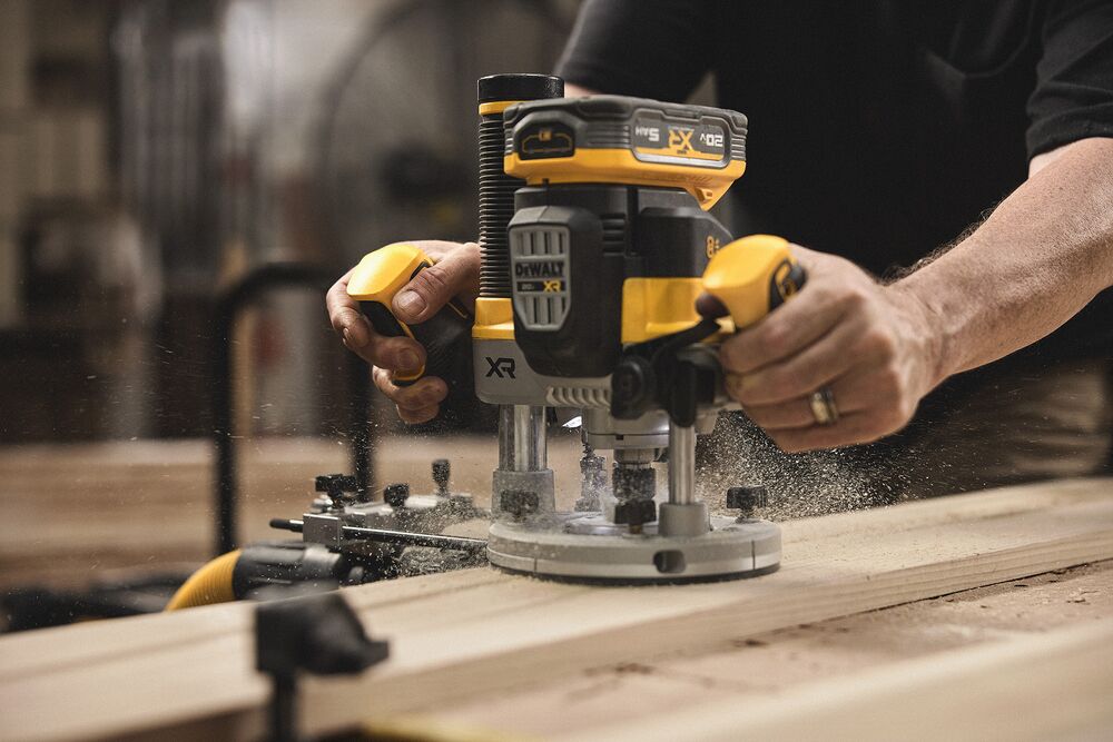 A tradesperson uses a DEWALT router on a piece of wood in a woodshop