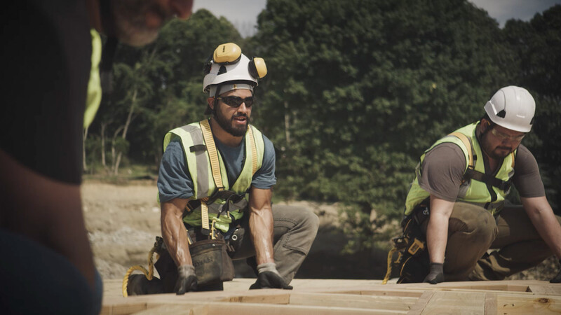 Two tradespeople prepare to hoist a frame up