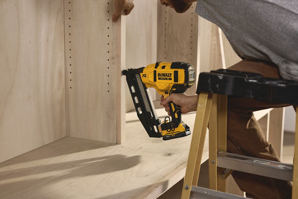 A tradesperson uses a DEWALT nailer to install cabinets