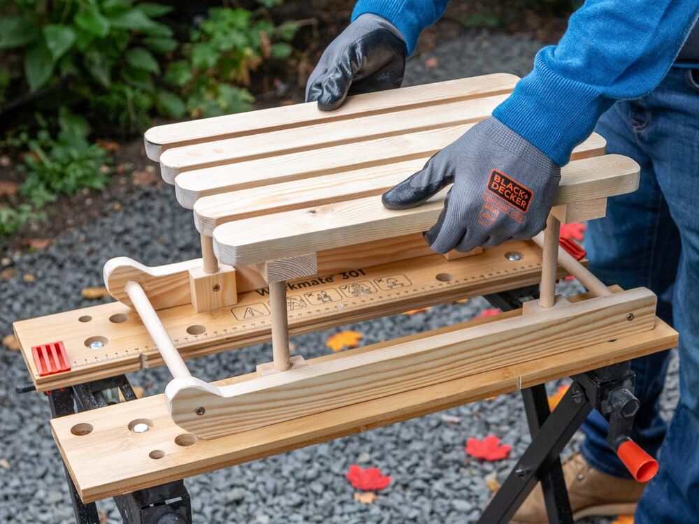 The seat of a wooden mini sleigh being attached to a base.