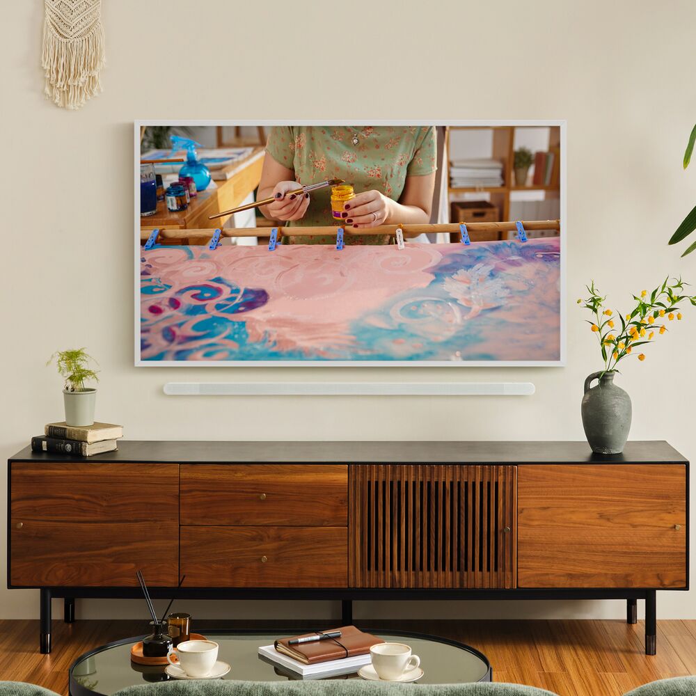 A Samsung 'The Frame' QLED Television wall-mounted above a side table.