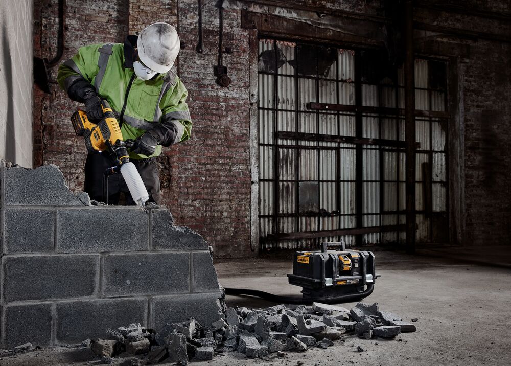 60 Volt MAX 1 and quarter inch Brushless S D S PLUS Rotary Hammer kit being used for breaking concrete wall by person.
