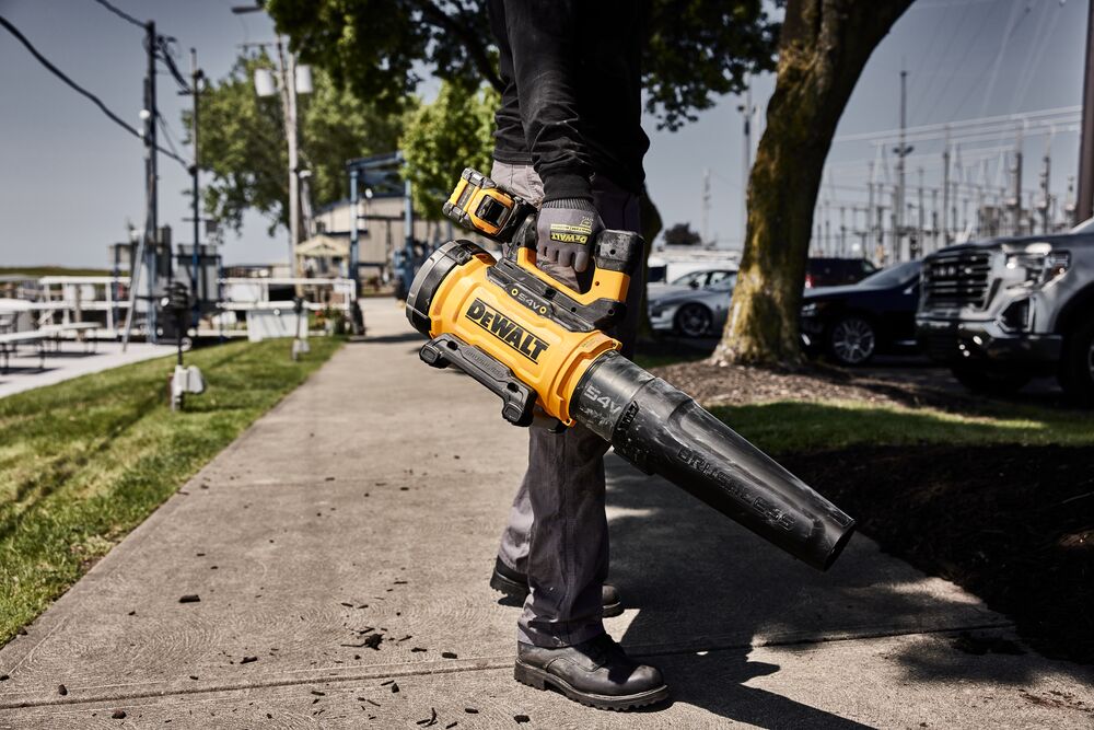 Worker standing on pavement holding 54V Axial Blower DCMBL777