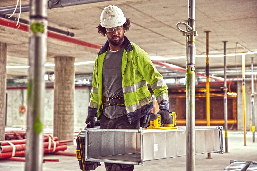 Construction worker using a Grabo 18V XR Suction Lifter to carry metal duct framework