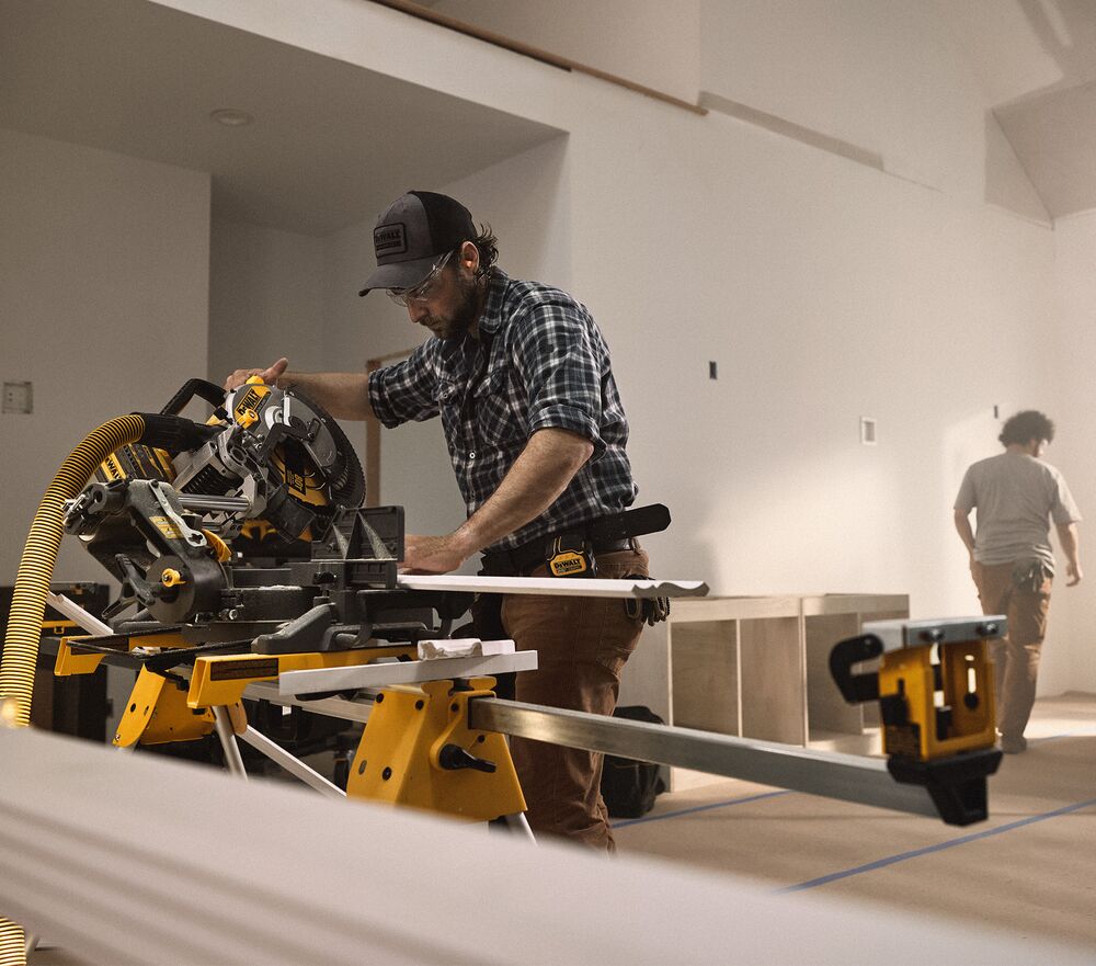 A tradesperson uses a DEWALT miter saw to cut trim pieces