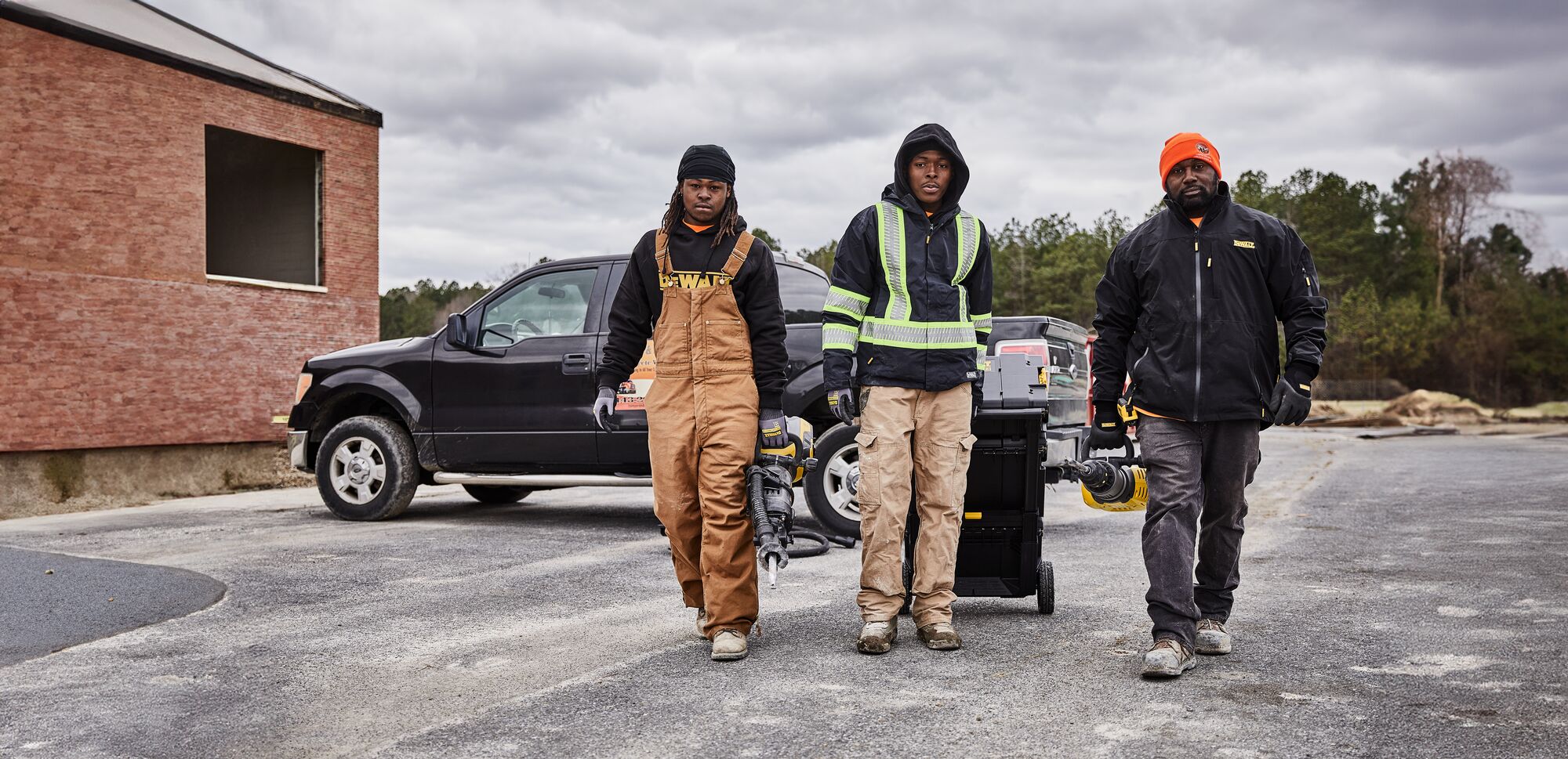 Three people carrying DEWALT Tools to the jobsite