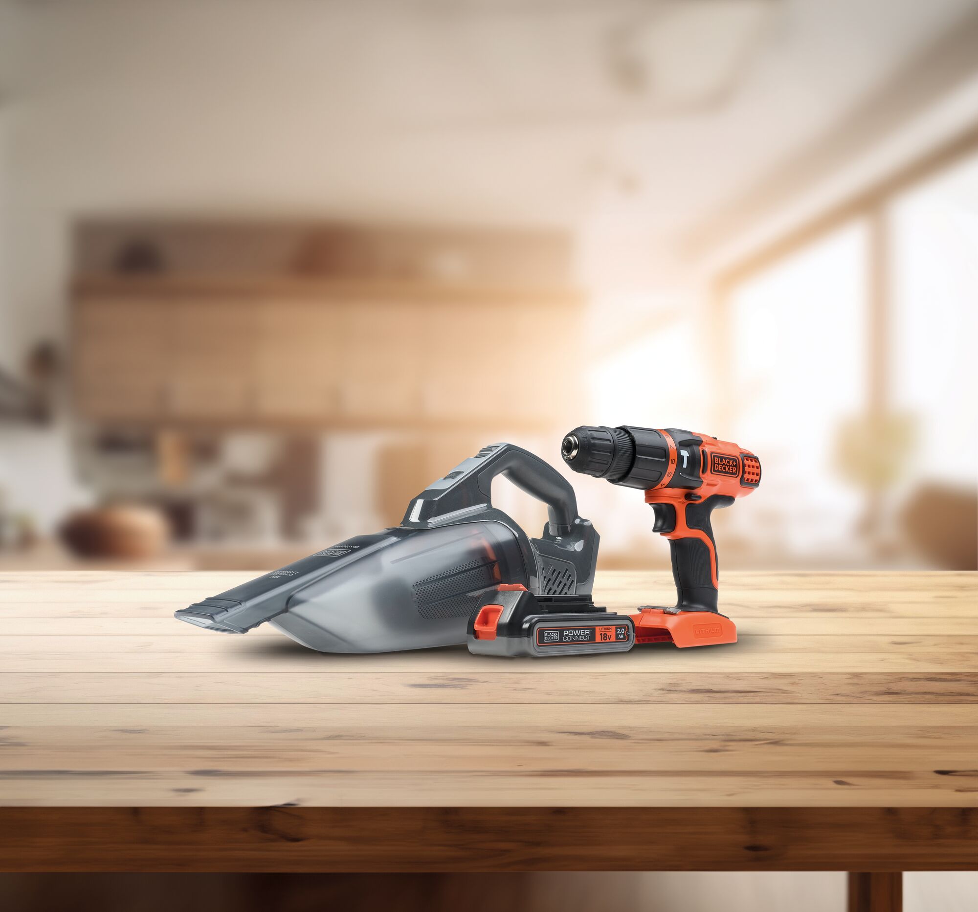 Three Black and Decker products,  a hand vacuum, drill and battery on a wooden table.