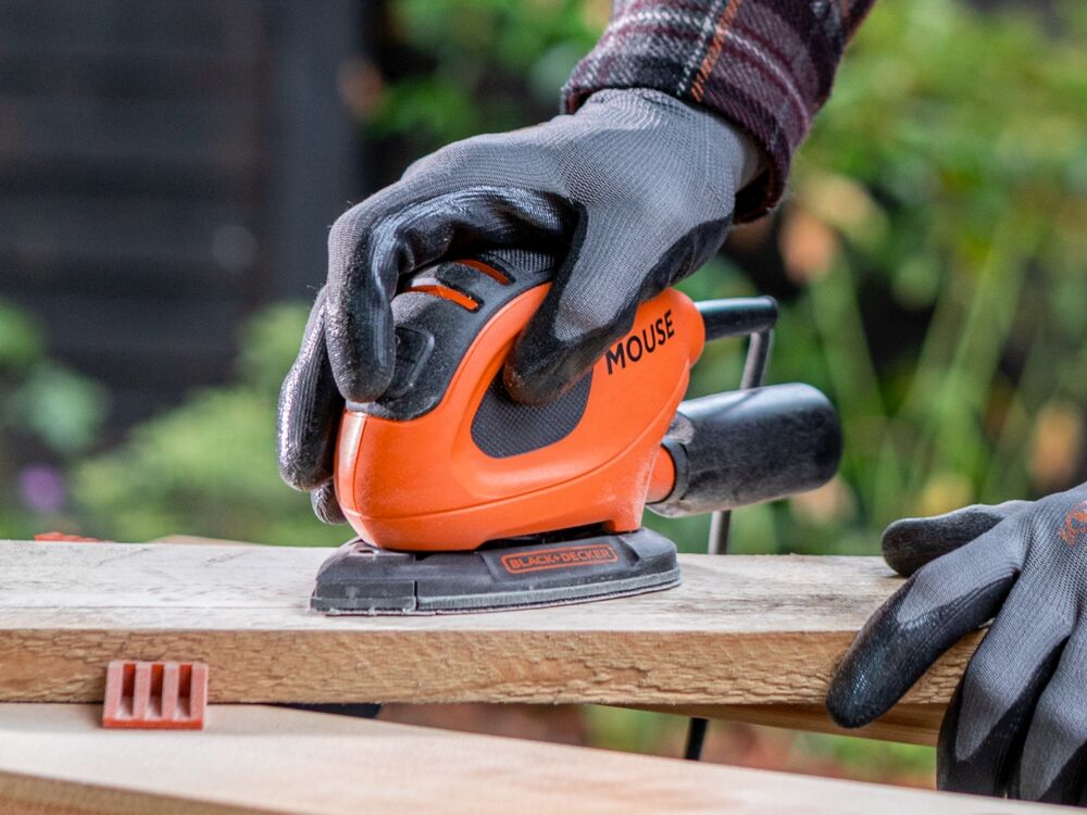 A wooden plank being sanded with the BLACK+DECKER 55W MOUSE Detail Sander.