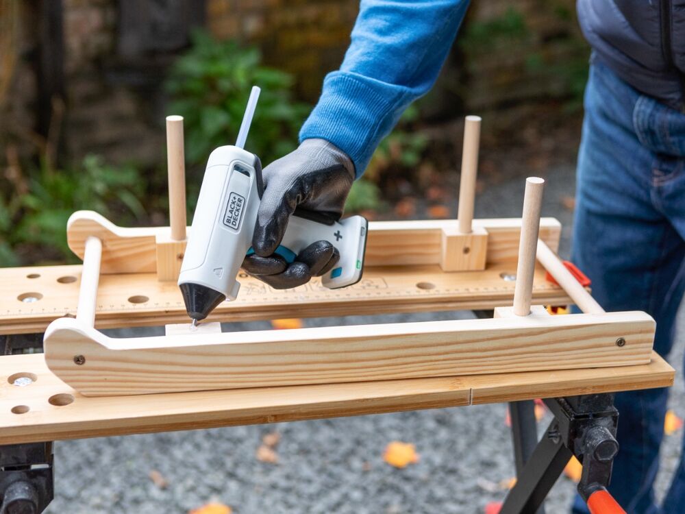 Glue being applied to a wooden mini sleigh frame using the BLACK+DECKER 3.6V Cordless Glue Gun.