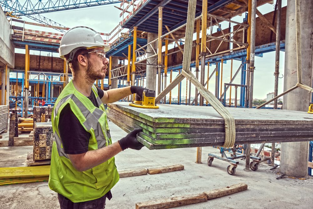 Construction worker uses a  Grabo 18V XR Suction Lifter to guide a large delivery of timber