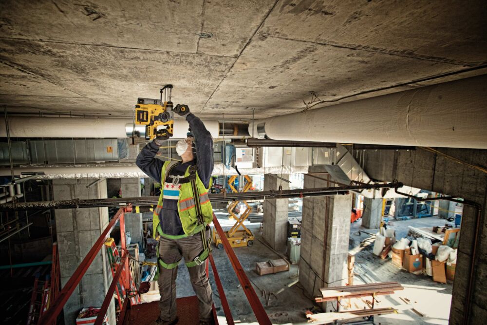 Brushless, cordless SDS PLUS L-shape rotary hammer being used by a person