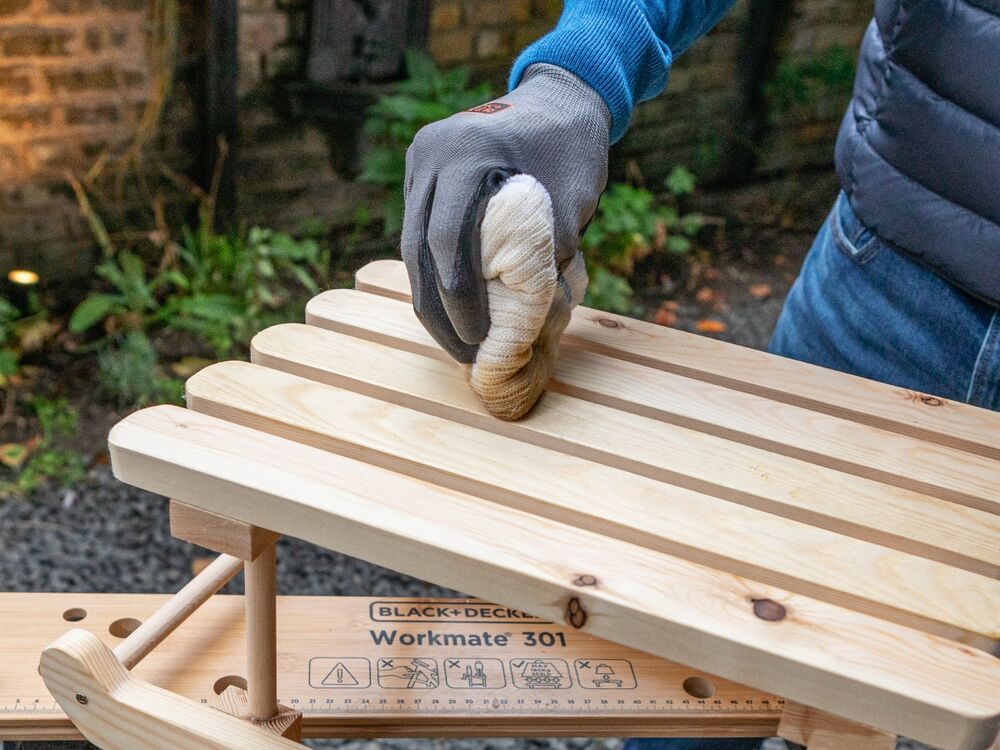 Danish oil being applied to a wooden mini sleigh.