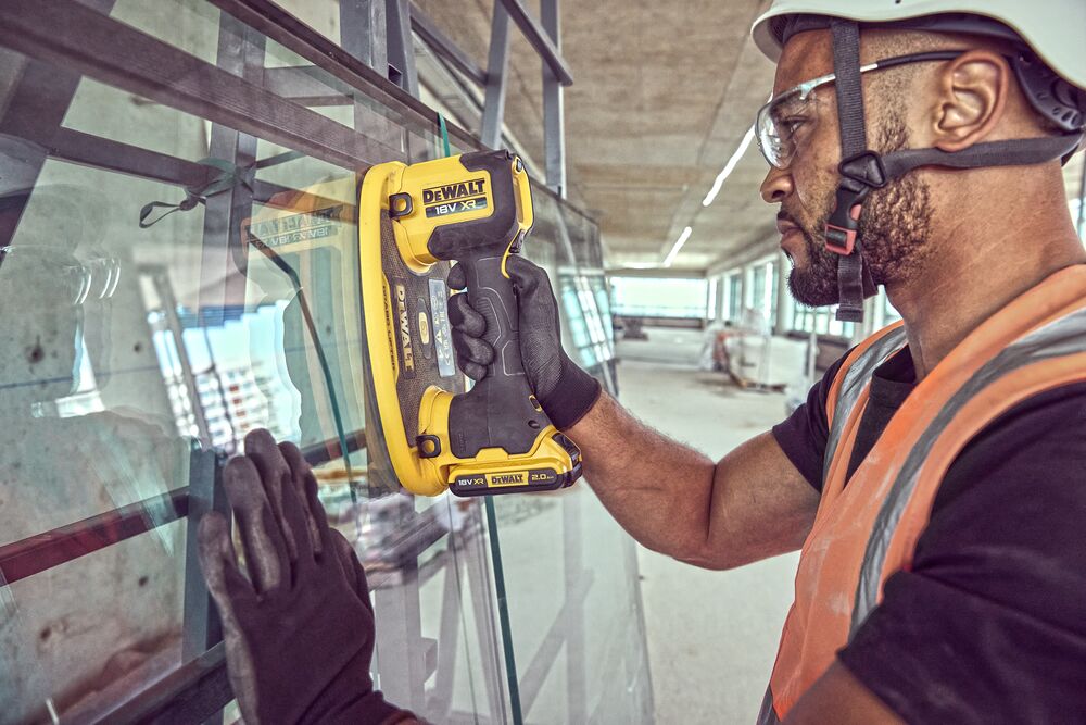 Construction worker attaches a Grabo 18V XR Suction Lifter to a pane of glass