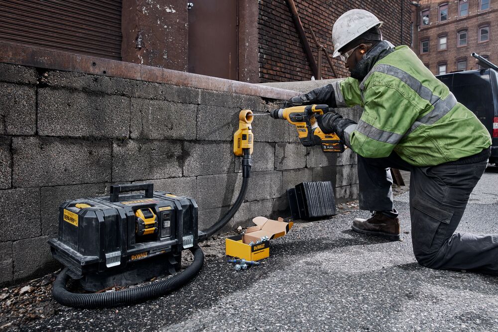 60 Volt MAX 1 and quarter inch Brushless S D S PLUS Rotary Hammer kit being used for drilling hole concrete wall by person.
