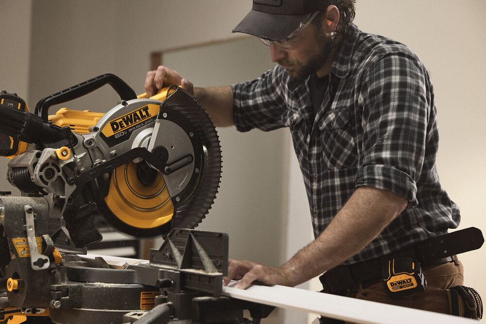 A tradesperson uses a DEWALT miter saw to cut trim pieces