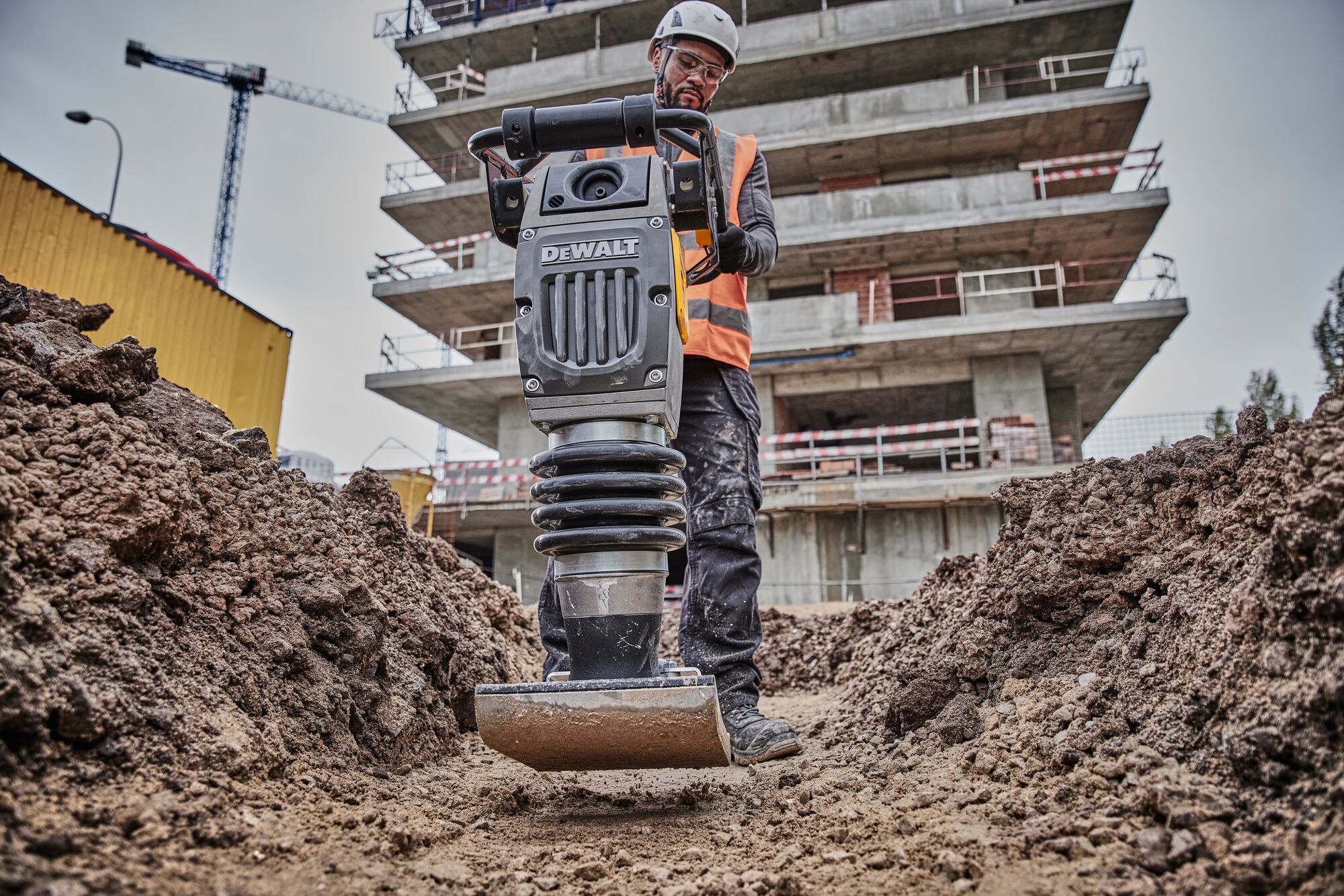 Man operating rammer in dirt trench