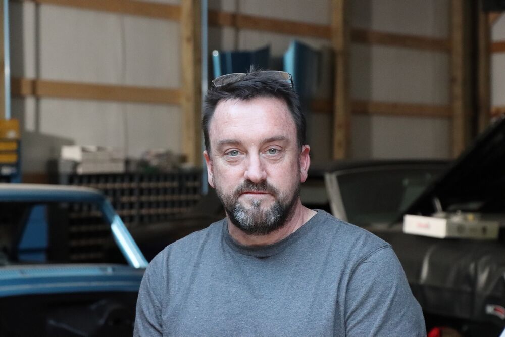 Chris Gilligan, aka Spider, looks into the camera while sitting in a garage