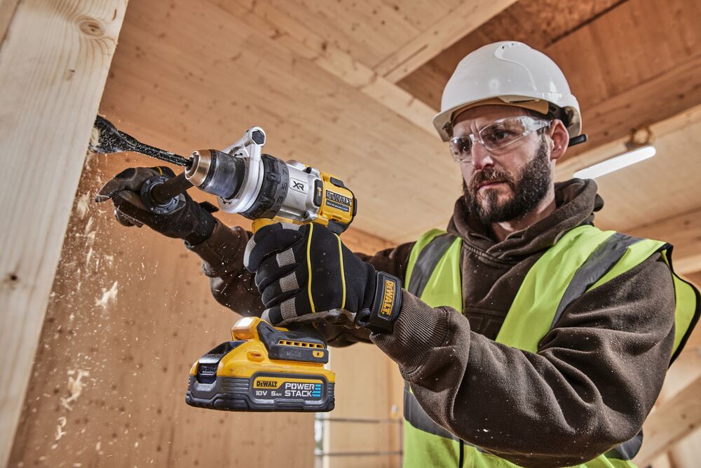 Construction worker using 18V XR Brushless Premium Hammer Drill Driver with 5Ah Powerstack to drill a hole in wood