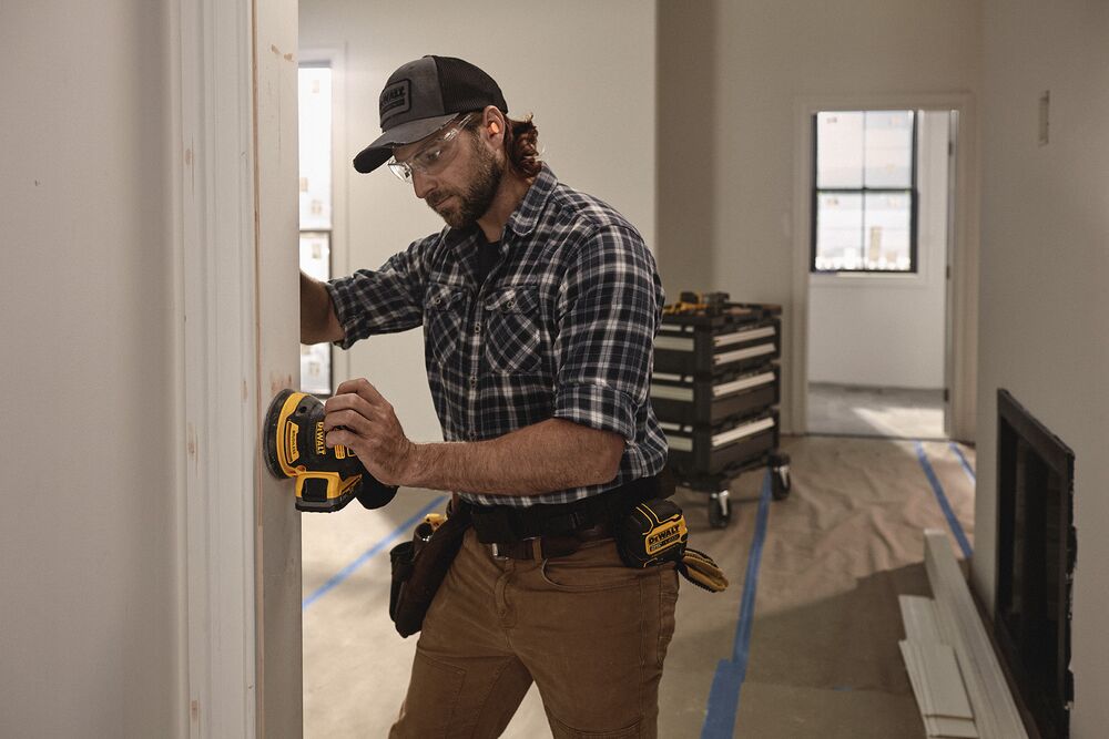 A tradesperson uses a DEWALT sander to finish trimwork