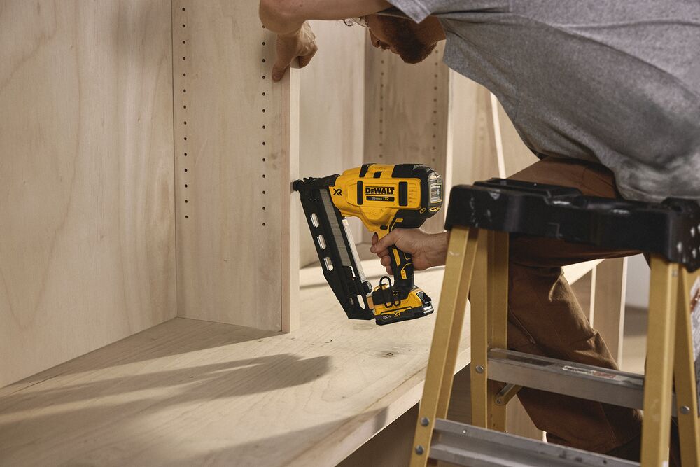 A tradesperson uses a DEWALT nailer to install cabinets