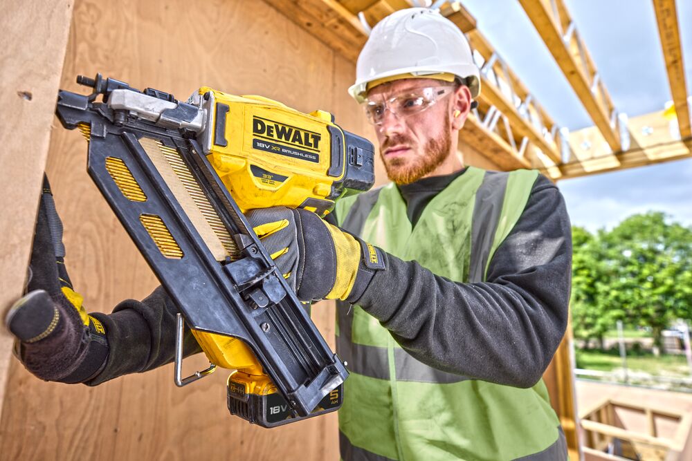 Worker using DCN930 18V XR Brushless framing nailer to drive nails into a wooden frame