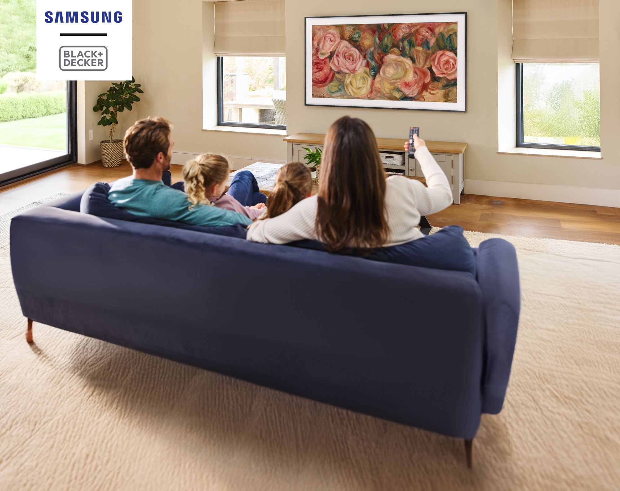 A family sit on a sofa to watch a Samsung 'The Frame' QLED Television.