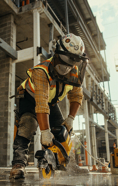 A concrete mason uses a DEWALT saw to cut into concrete