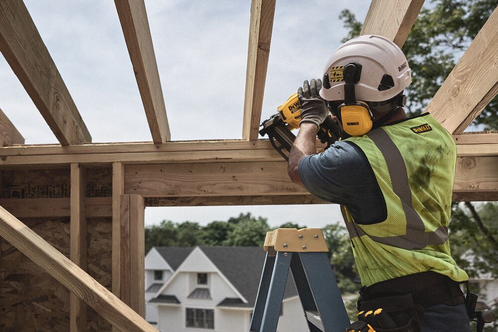 A tradesperson uses a DEWALT nailer  on a frame