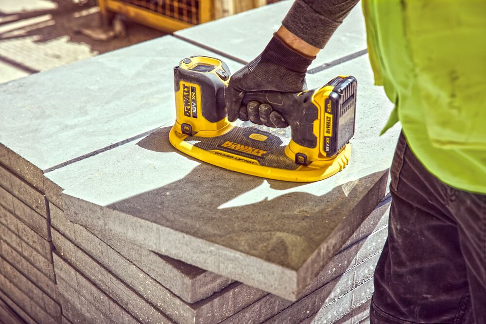 Construction worker holds a Grabo 18V XR Suction Lifter on top of a column of concrete blocks