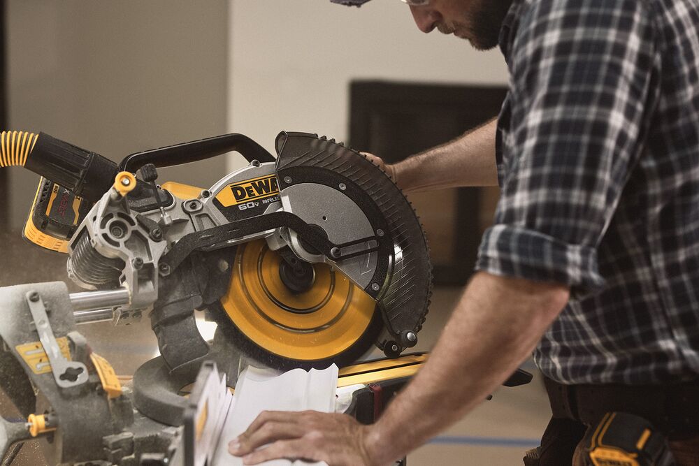 A tradesperson uses a DEWALT miter saw to cut trim pieces