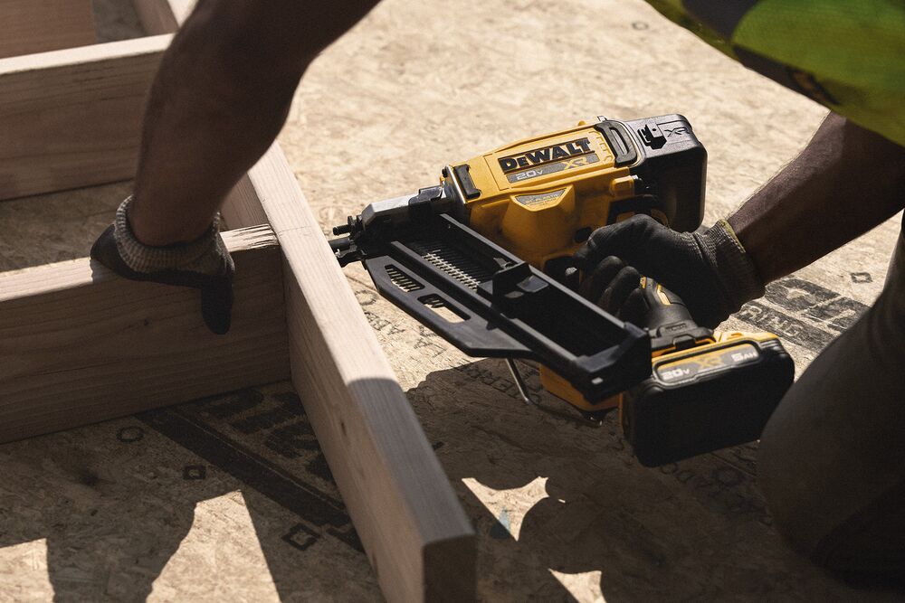 A tradesperson uses a DEWALT nailer  on a frame