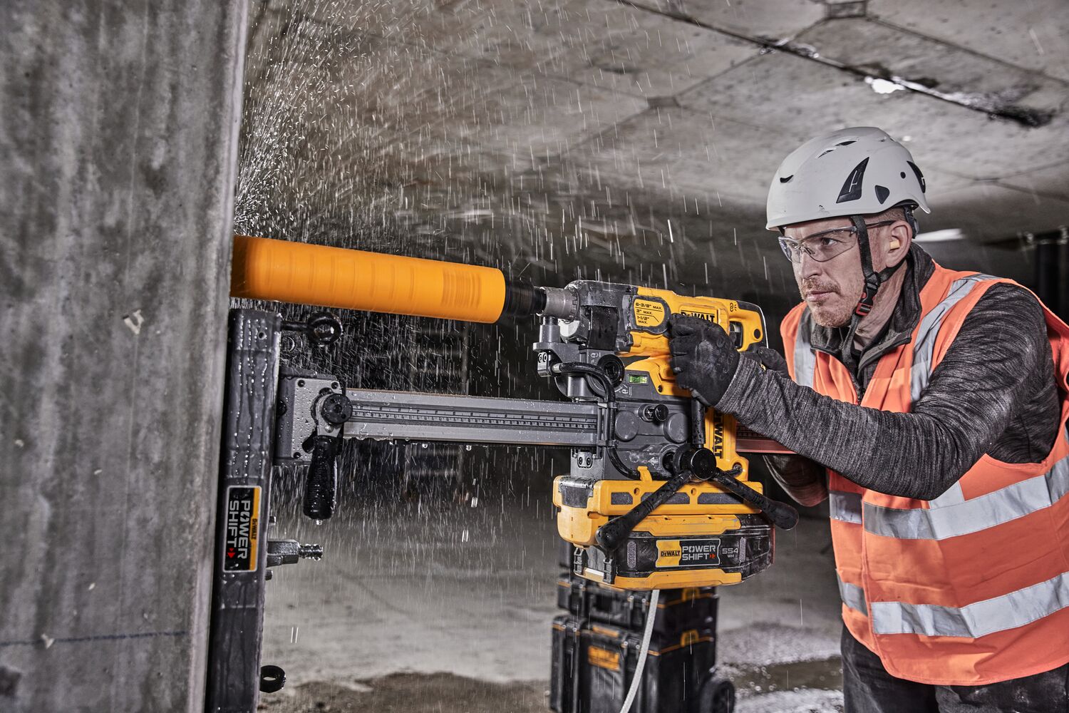 Angled view of DCPS151 Powershift Diamond Drill Stand being used with Diamond Drill DCD150 and DCE6820 water tank to vertically core drill concrete