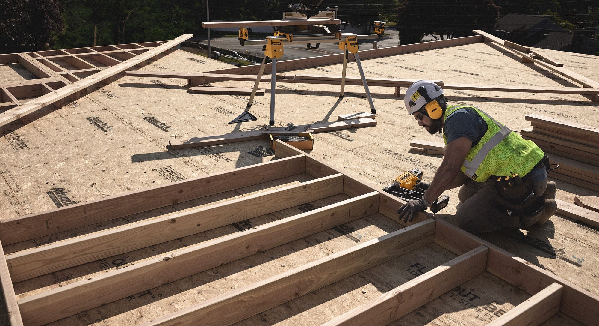 A tradesperson uses a DEWALT nailer  on a frame