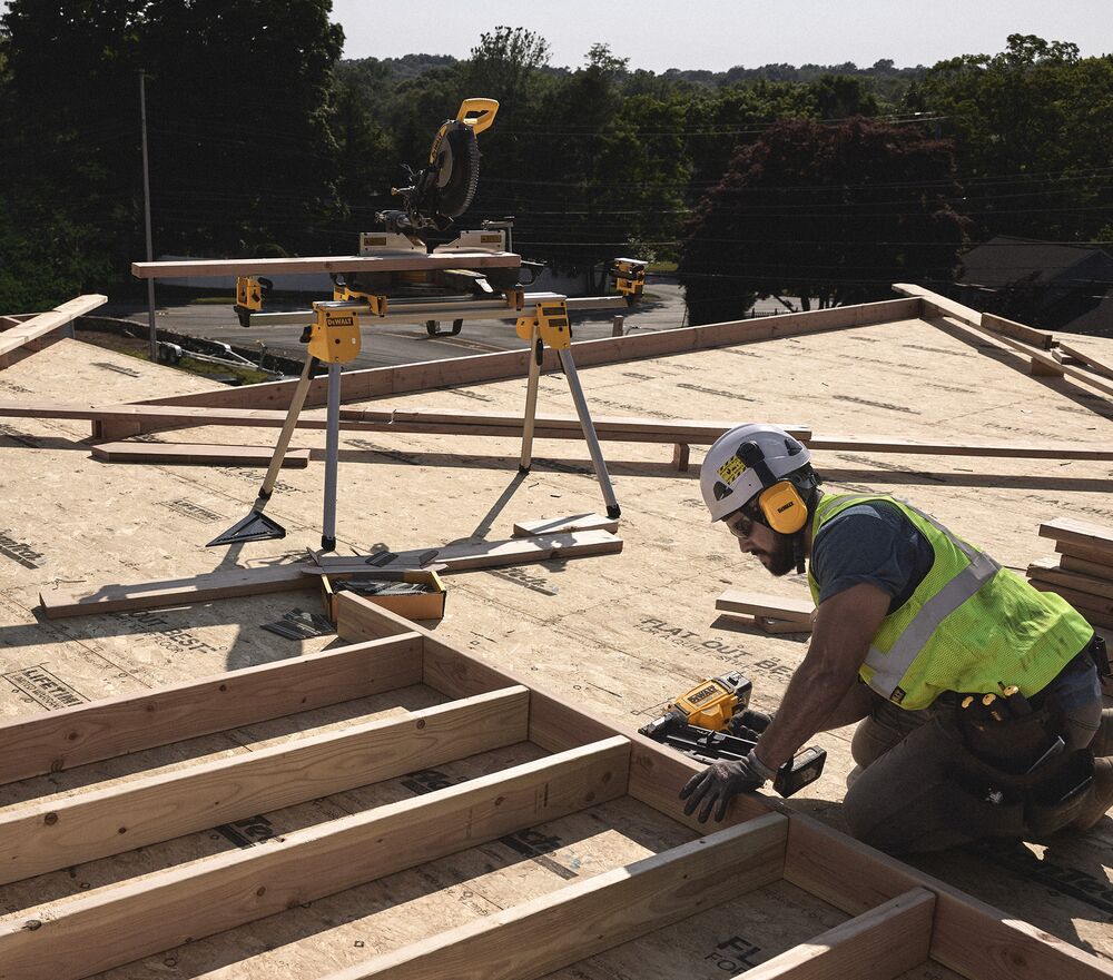 A tradesperson uses a DEWALT nailer  on a frame