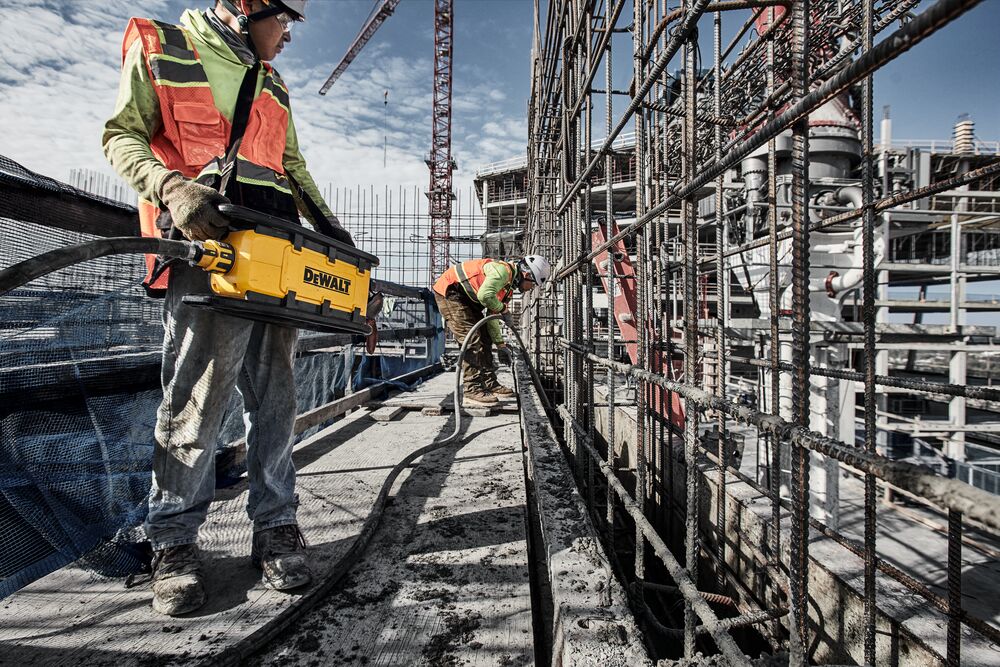 Two construction workers use Powershift Powerpack Concrete Vibrator and hose to pour concerte into a channel