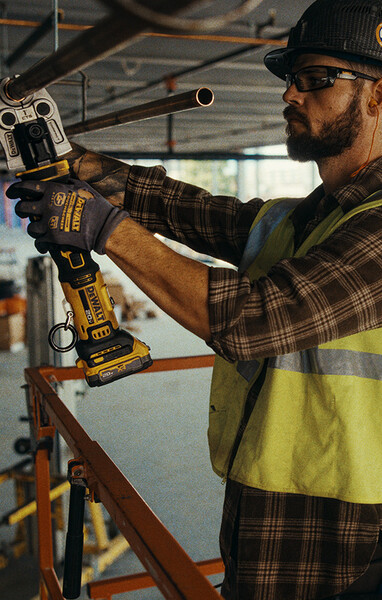 A plumber uses a DEWALT compact press on the job