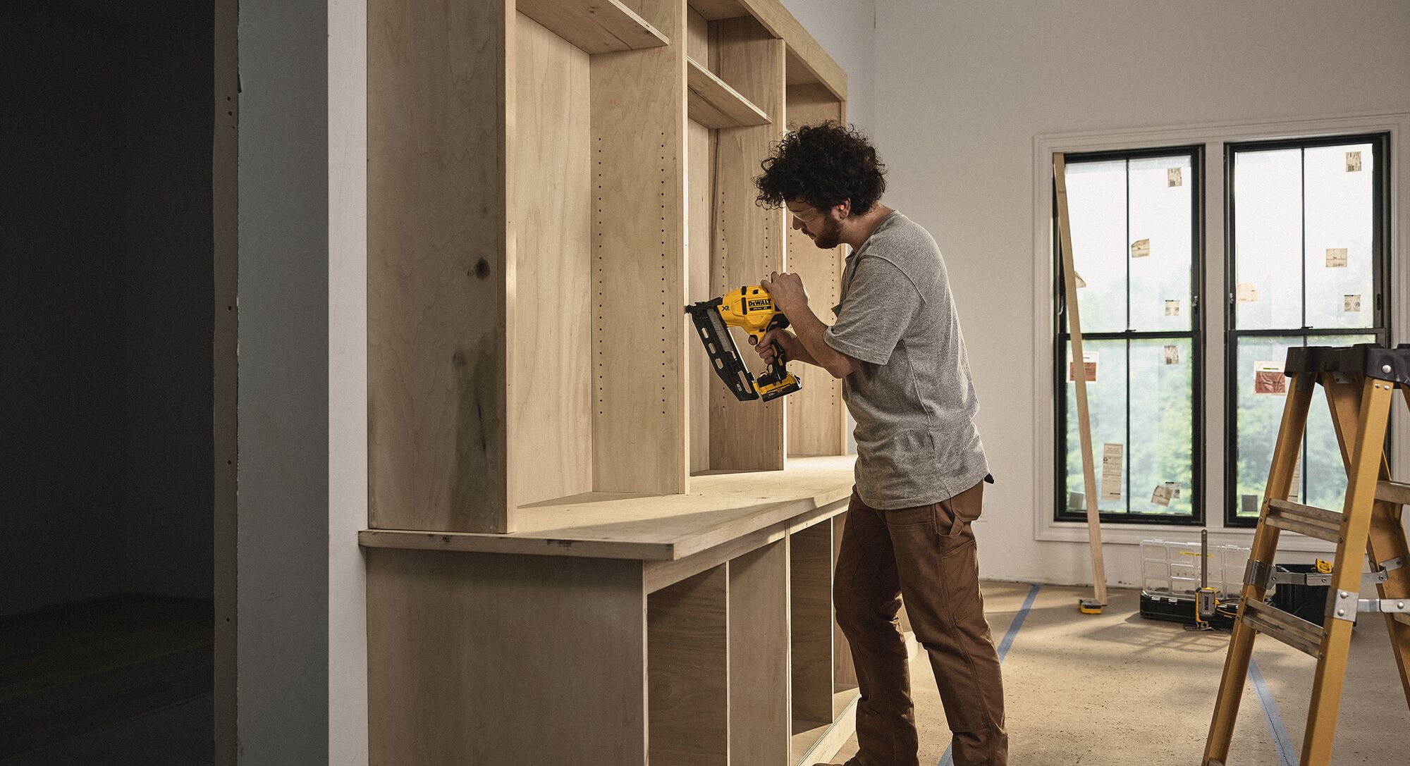 A tradesperson uses a DEWALT nailer to install cabinets