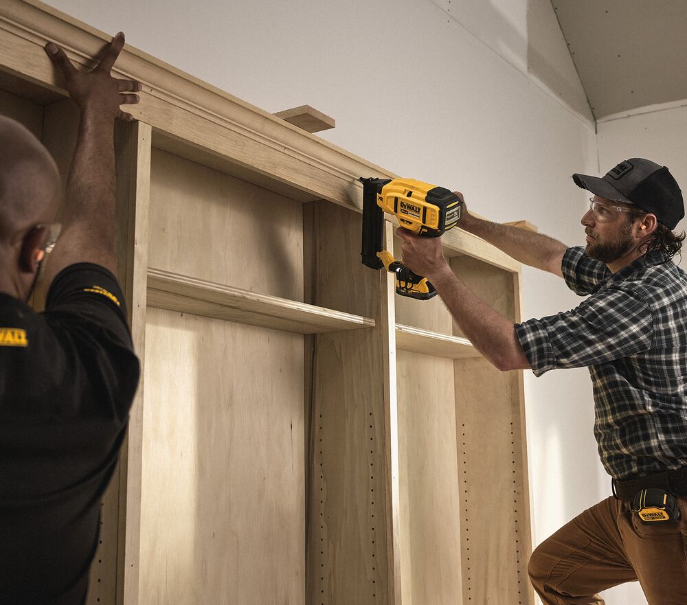 A tradesperson uses a DEWALT nailer to install cabinets