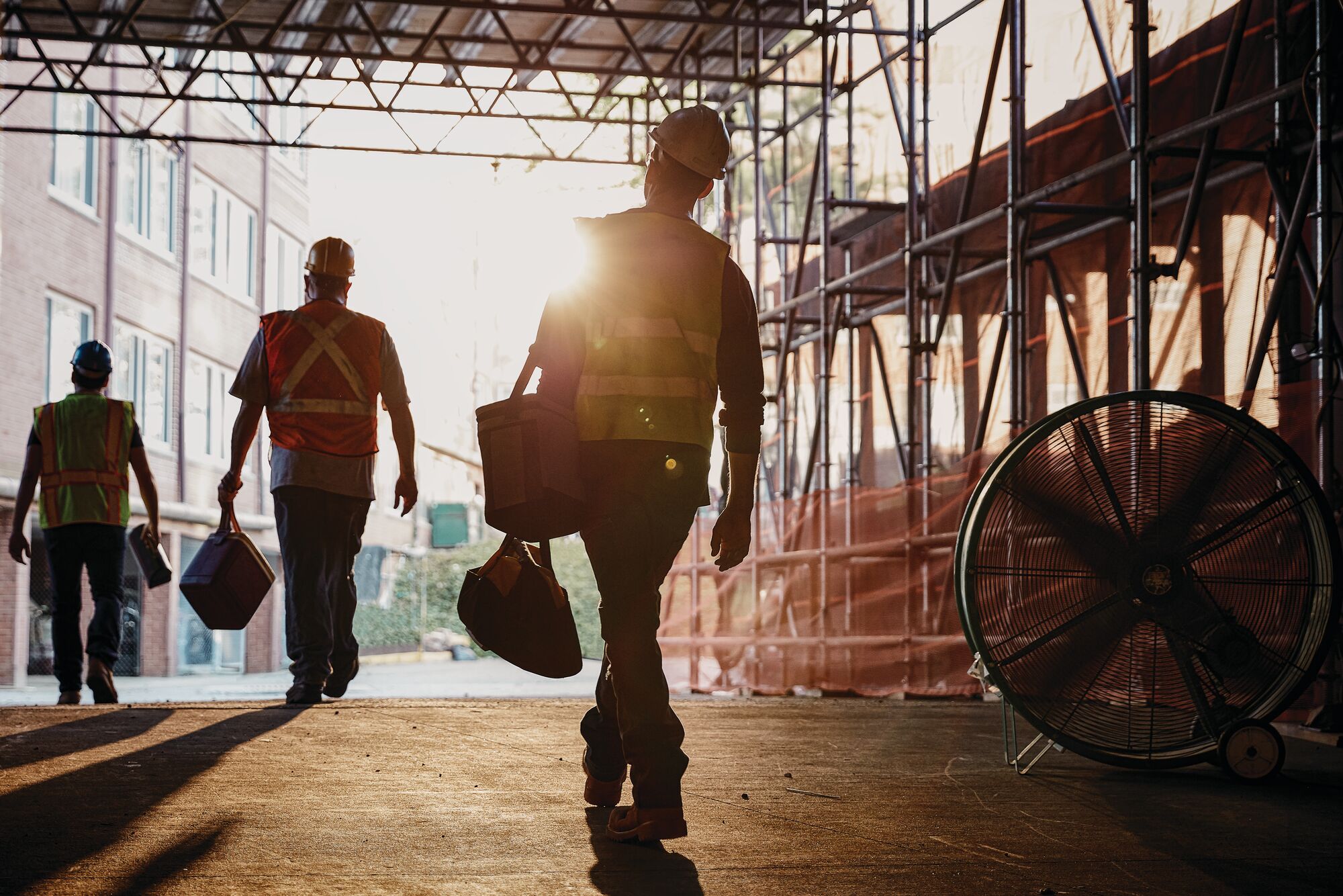 Image of three construction workers with ppe walking out of structure