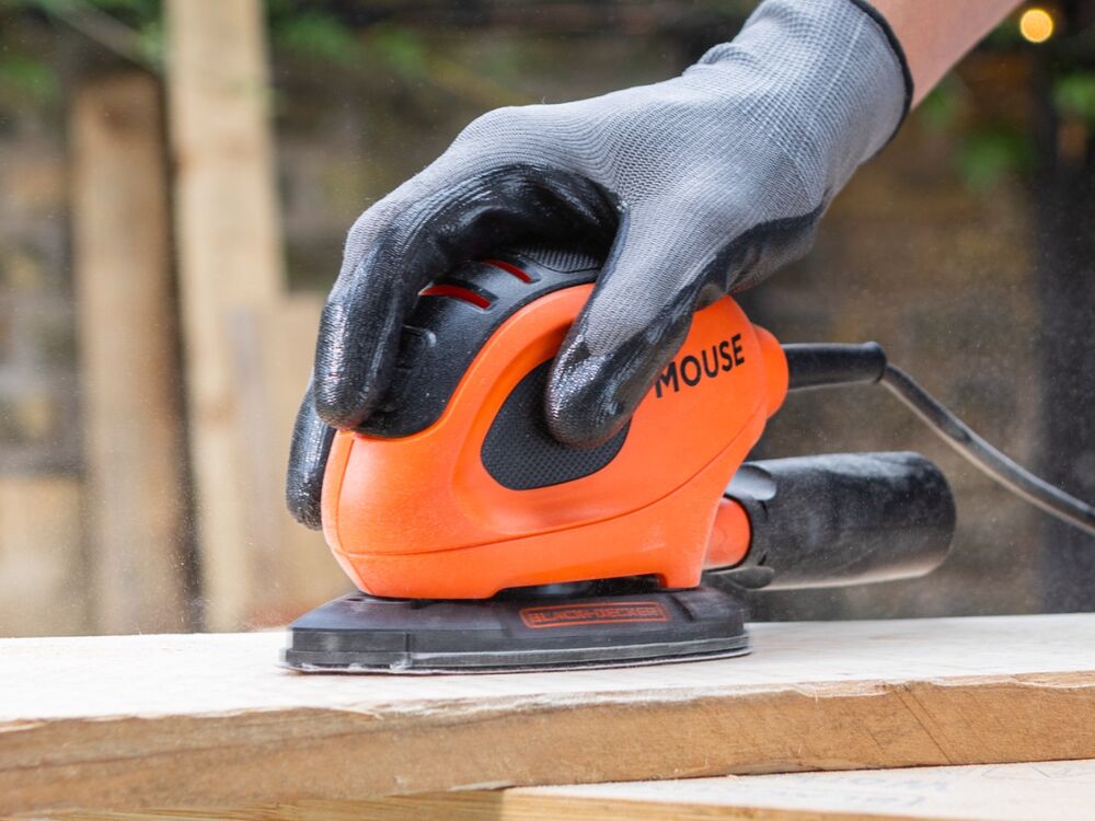 A wooden plank being sanded with the BLACK+DECKER 55W MOUSE Detail Sander.