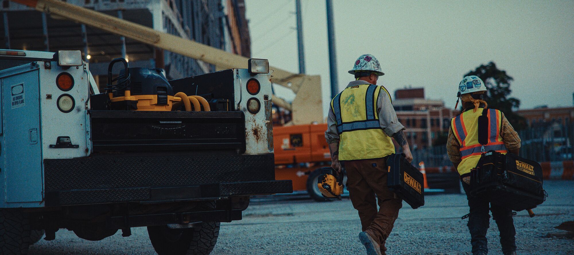 Two tradespeople walk to the jobsite with their DEWALT tools